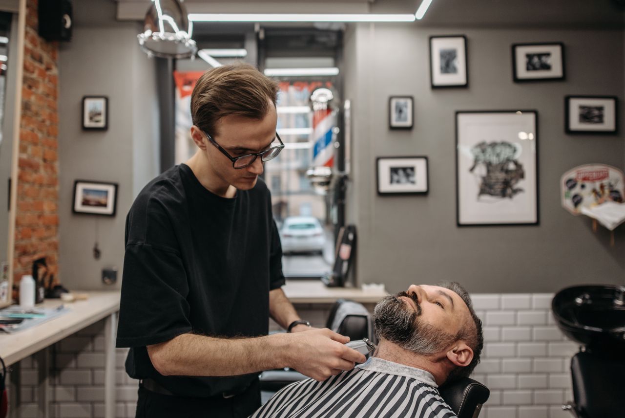 Barber refining hairline and beard edges during a grooming session